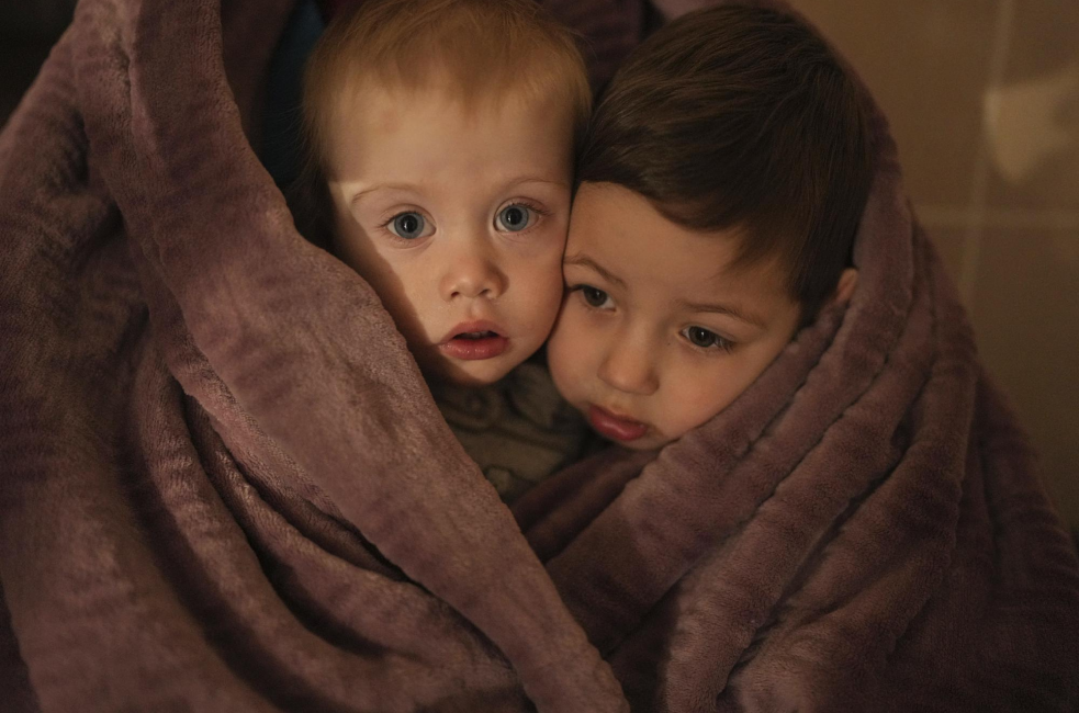 Two children with a blanket wrapped around them