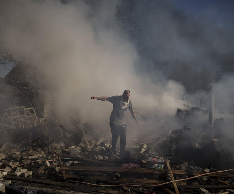 Man walking on the debris of a burning house destroyed after a Russian attack in Kharkiv, Ukraine